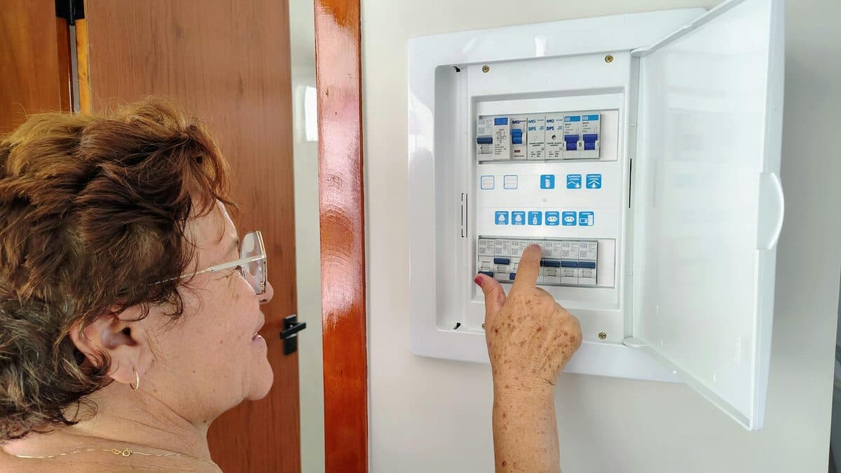 Senior woman looking at a residential electrical circuit breaker panel indoors