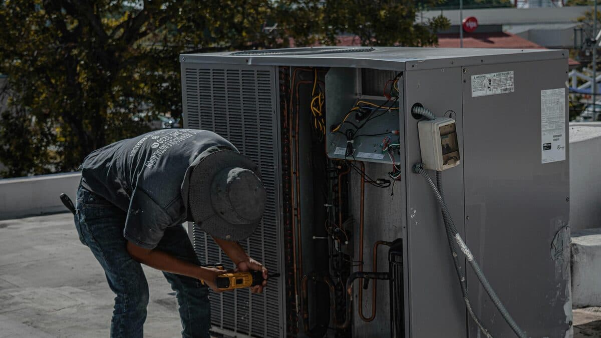 HVAC technician inspecting and repairing an outdoor air conditioning unit